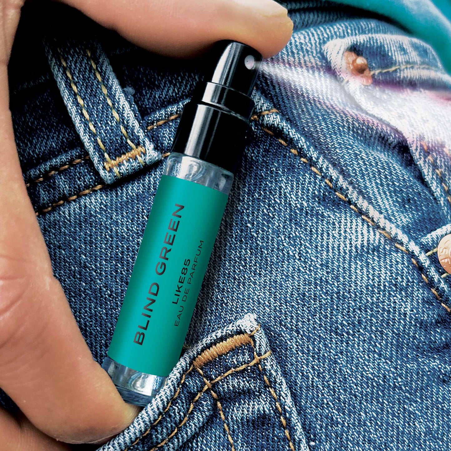 Hand holding a small green bottle labeled 'Blind Green' against a denim background