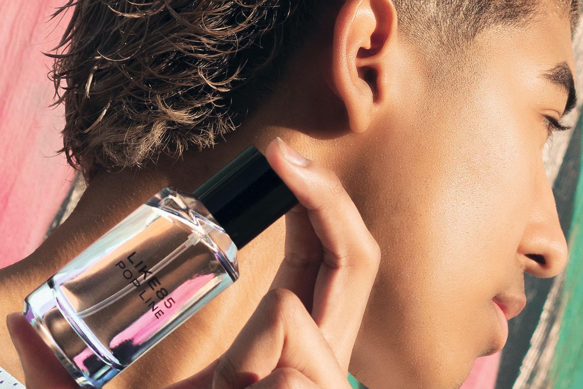 Person holding a perfume bottle close to their ear