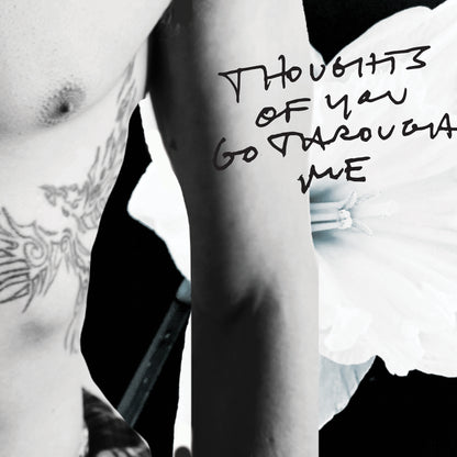 Black and white close-up of a person's arm with text 'Thoughts of you go through me' written on it.